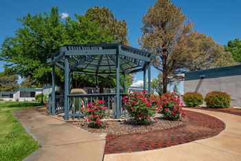 a gazebo with flowers and trees in the background
